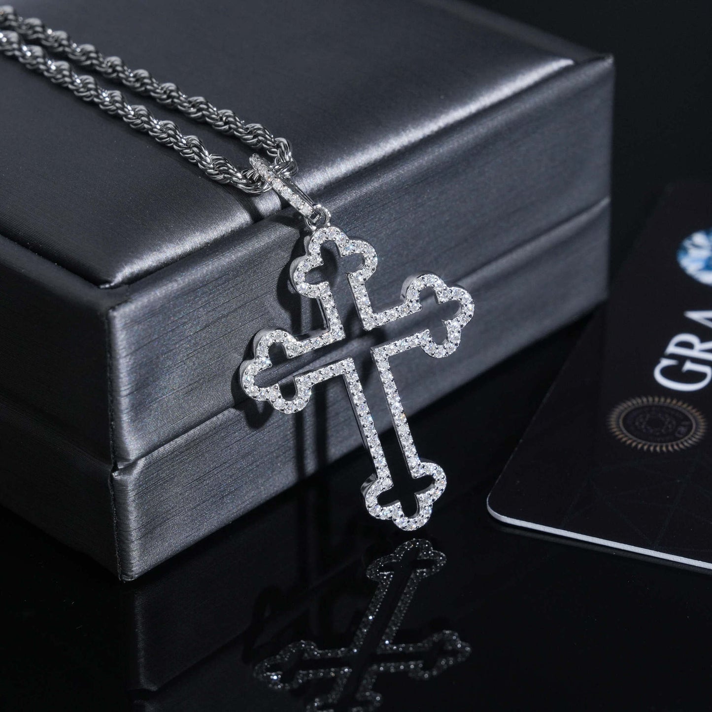 Silver cross necklace on a black box with a card in the background