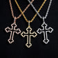 Three cross-shaped pendants on different colored chains against a black background