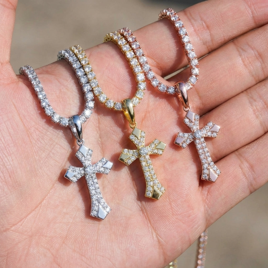 Three diamond-cross pendants on chains held in a hand.