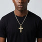 Man wearing a black t-shirt with a gold cross necklace against a gray background