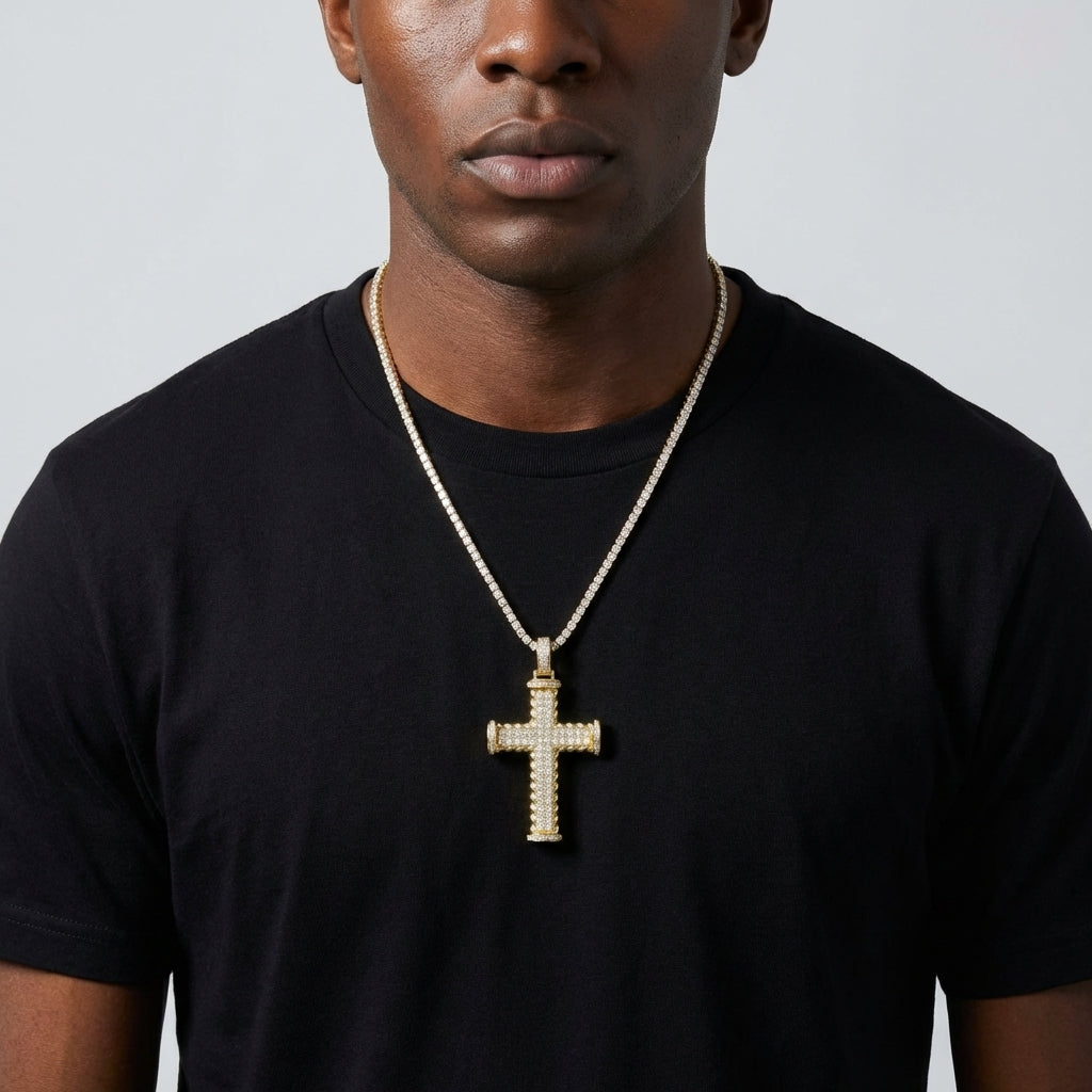 Man wearing a black t-shirt with a gold cross necklace against a gray background