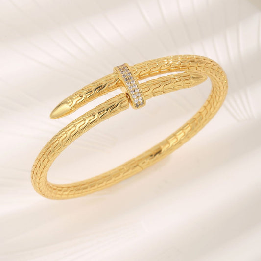 Gold bracelet with textured design on a light background