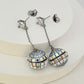 Earrings on a soft black or silver glitter background, showcasing the linear cascade of mirror tiles catching light. Alt: “Kate Spade Beaming Bright Disco Ball Linear Earrings – Mirror Tile Drop Jewelry.”
