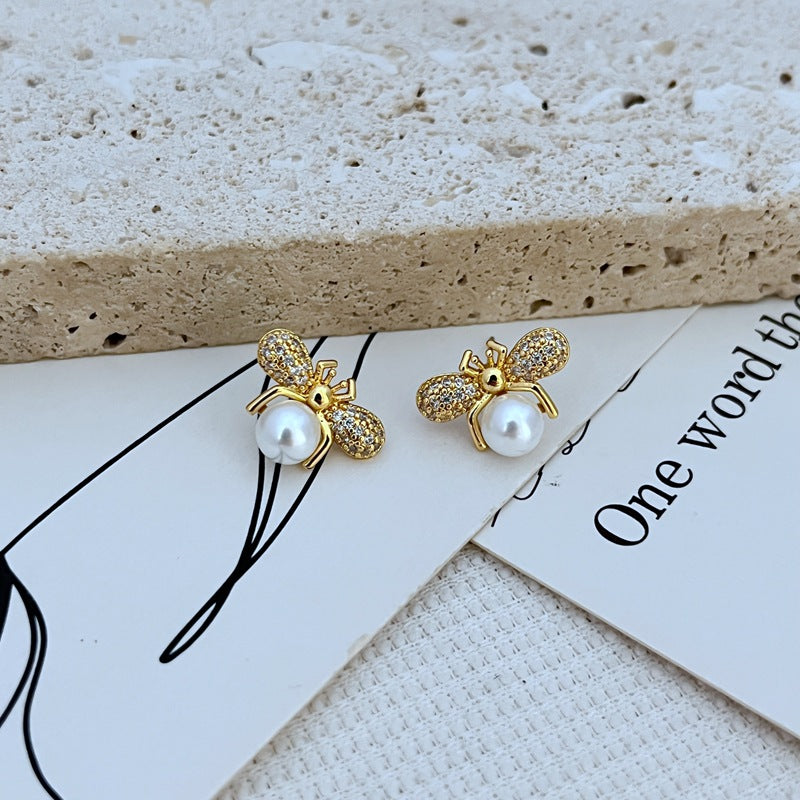 Earrings on a clean white or soft honeycomb-patterned background, showcasing the detailed bee design. Alt: “Kate Spade Bee Earrings – Gold Enamel Bee Stud Jewelry.”