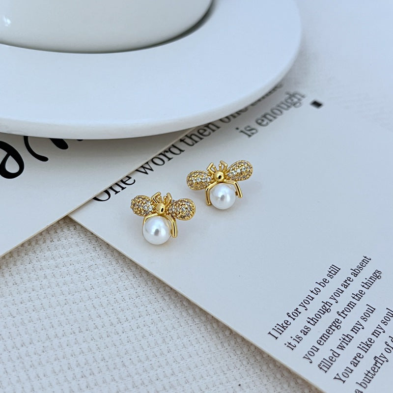 Earrings on a clean white or soft honeycomb-patterned background, showcasing the detailed bee design. Alt: “Kate Spade Bee Earrings – Gold Enamel Bee Stud Jewelry.”