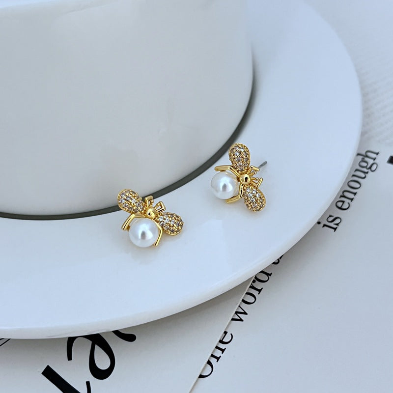 Earrings on a clean white or soft honeycomb-patterned background, showcasing the detailed bee design. Alt: “Kate Spade Bee Earrings – Gold Enamel Bee Stud Jewelry.”