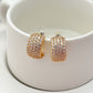 Gold-tone huggie hoops fully pavé-set with crystals on a soft white or champagne background. Alt: “Kate Spade Brilliant Statements Gold Pavé Huggies – Full Crystal Hoop Earrings.”