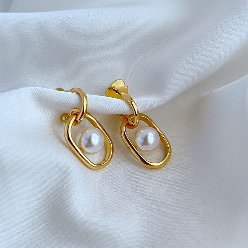 Earrings on a soft cream or dove grey background, showcasing the cascading gold links and luminous pearl drop. Alt: “Kate Spade Chain Reaction Gold Plated Link Drop Pearl Earrings – Modern Pearl Jewelry.”