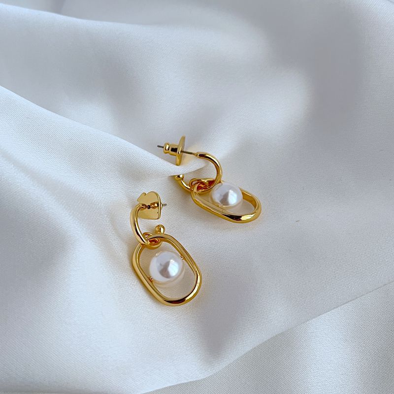 Earrings on a soft cream or dove grey background, showcasing the cascading gold links and luminous pearl drop. Alt: “Kate Spade Chain Reaction Gold Plated Link Drop Pearl Earrings – Modern Pearl Jewelry.”