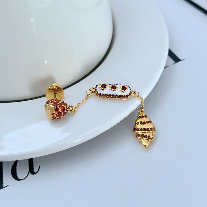  Earrings displayed side by side on a soft cream or café au lait background, showcasing the cherry shortcake and croissant charms. Alt: “Kate Spade Cherry Shortcake and Croissant Earrings – French Bakery Enamel Jewelry.”