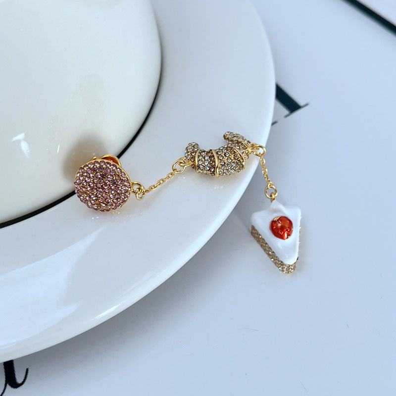  Earrings displayed side by side on a soft cream or café au lait background, showcasing the cherry shortcake and croissant charms. Alt: “Kate Spade Cherry Shortcake and Croissant Earrings – French Bakery Enamel Jewelry.”