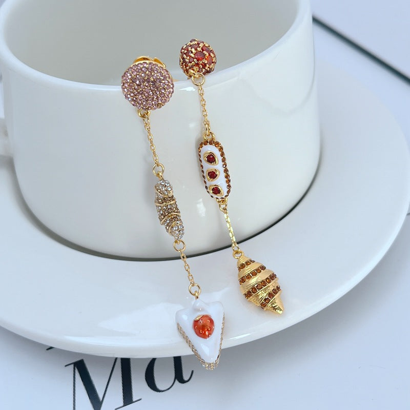  Earrings displayed side by side on a soft cream or café au lait background, showcasing the cherry shortcake and croissant charms. Alt: “Kate Spade Cherry Shortcake and Croissant Earrings – French Bakery Enamel Jewelry.”