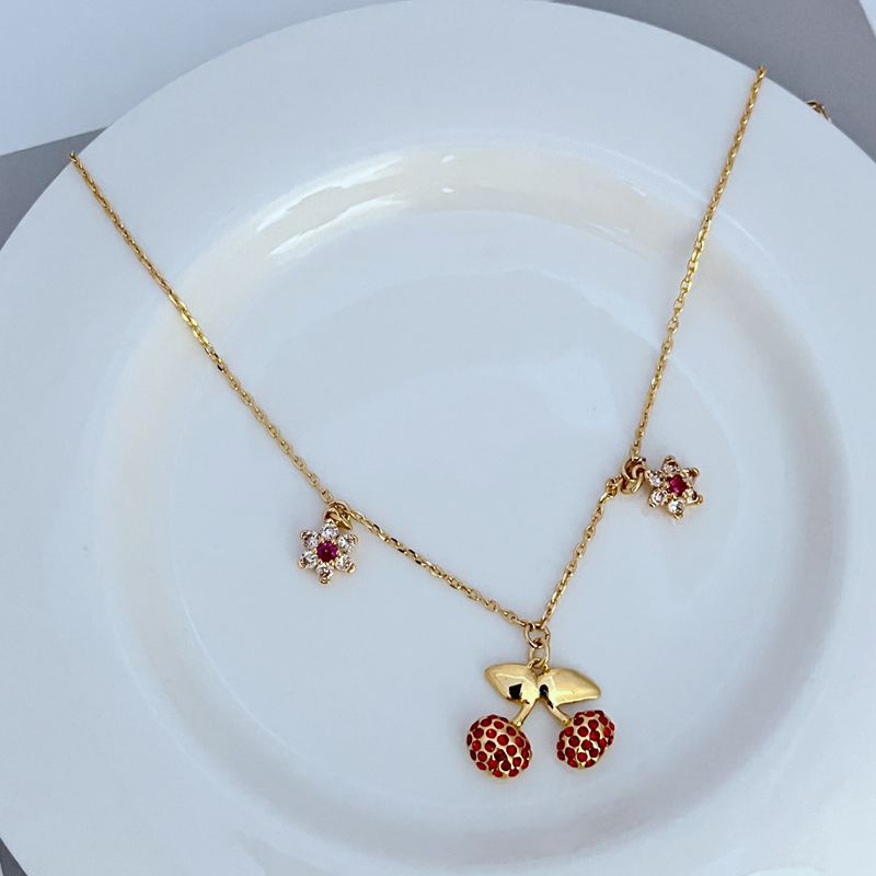 Necklace on a light, fresh background (white or soft green), highlighting the red and green enamel details. Alt: “Kate Spade Cherry and Flowers Necklace – Playful Botanical Charm Jewelry.”