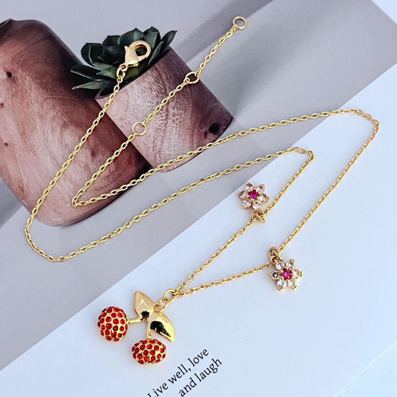  Necklace on a light, fresh background (white or soft green), highlighting the red and green enamel details. Alt: “Kate Spade Cherry and Flowers Necklace – Playful Botanical Charm Jewelry.”