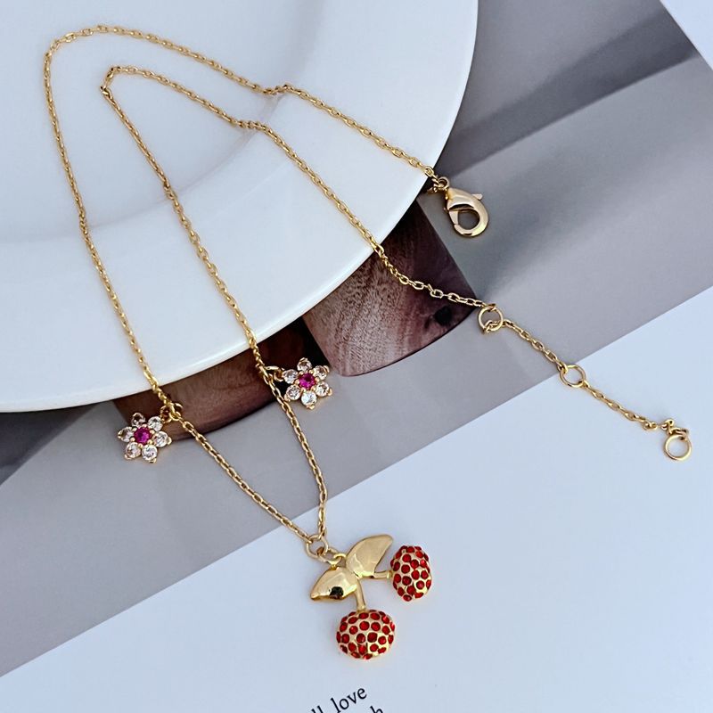  Necklace on a light, fresh background (white or soft green), highlighting the red and green enamel details. Alt: “Kate Spade Cherry and Flowers Necklace – Playful Botanical Charm Jewelry.”