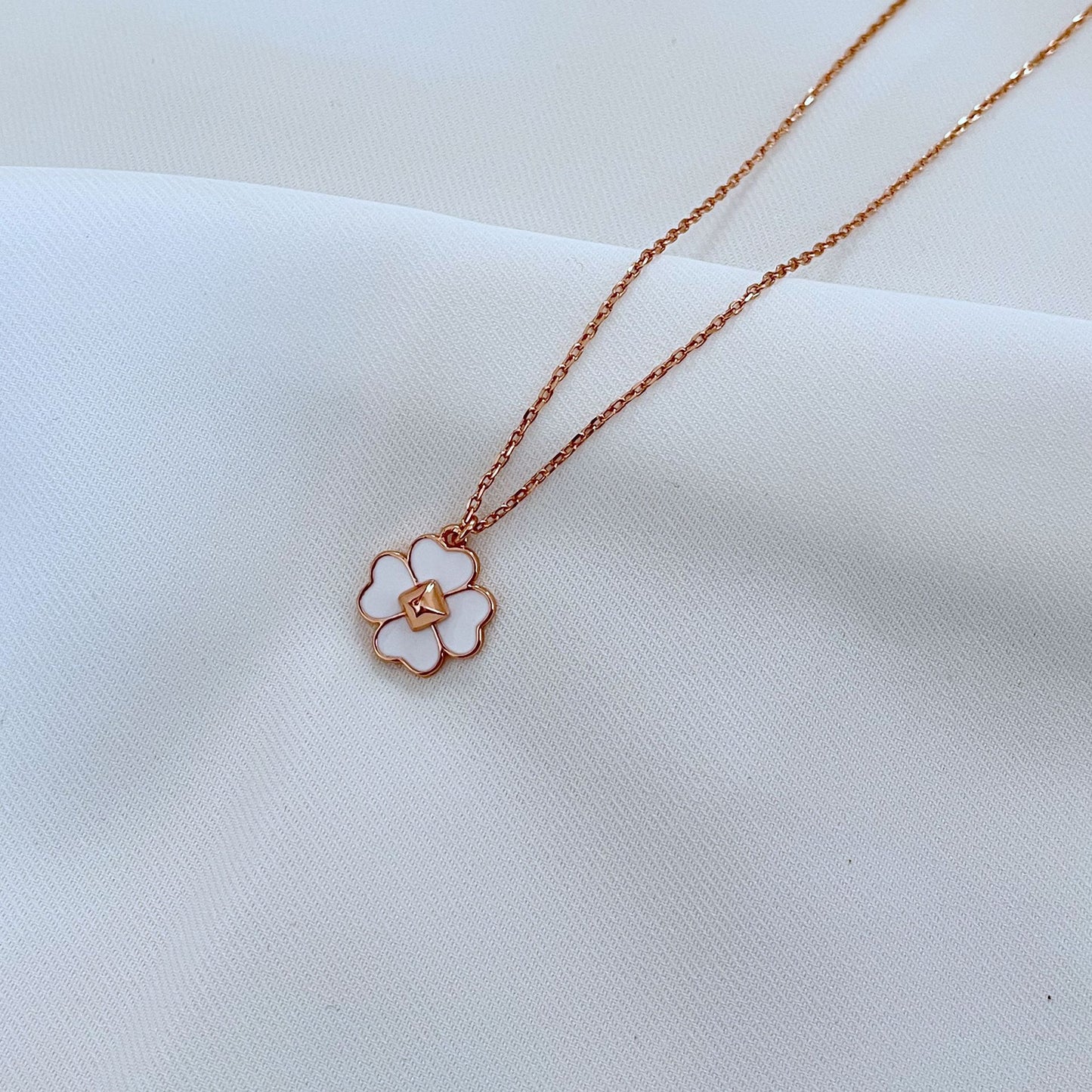 Clean, high-contrast shot of the necklace on a neutral background, highlighting the graphic interplay of gold and black on the clover.