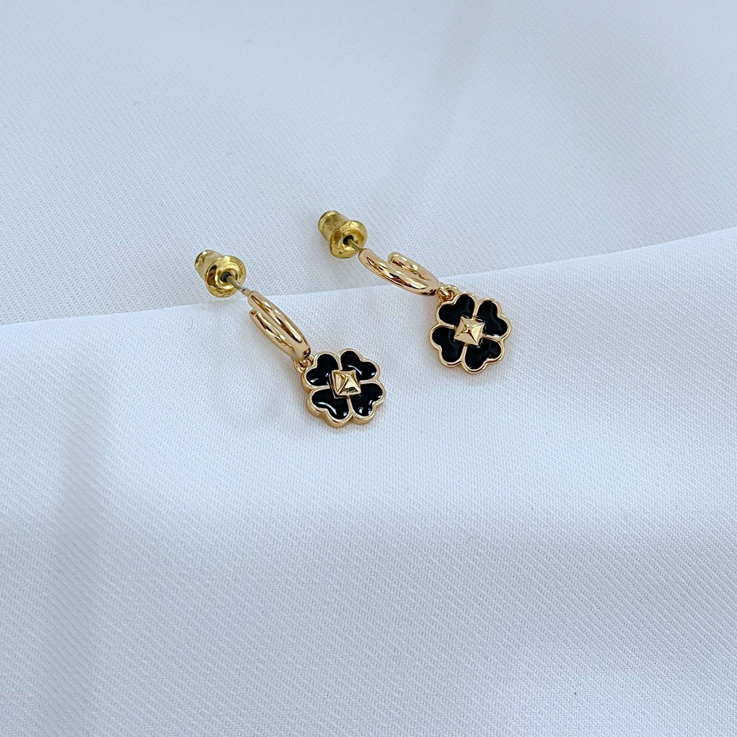 Macro shot focused on the pendant, showcasing the crisp lines between the enamel and metal, and the clover's shape.