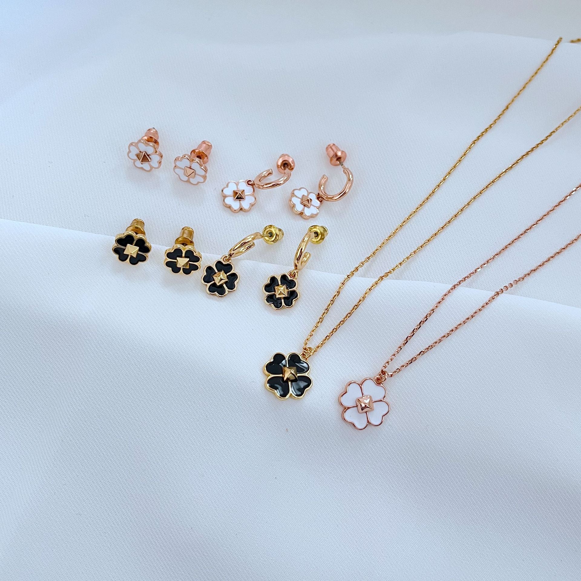 Clean, high-contrast shot of the necklace on a neutral background, highlighting the graphic interplay of gold and black on the clover.