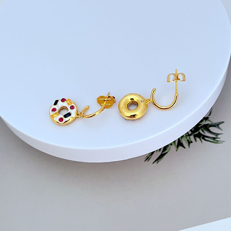 Earrings on a soft pastel pink or cream background, showcasing the donut and coffee charms dangling from huggie hoops. Alt: “Kate Spade Coffee Break Donut Huggies – Enamel Food Jewelry.”