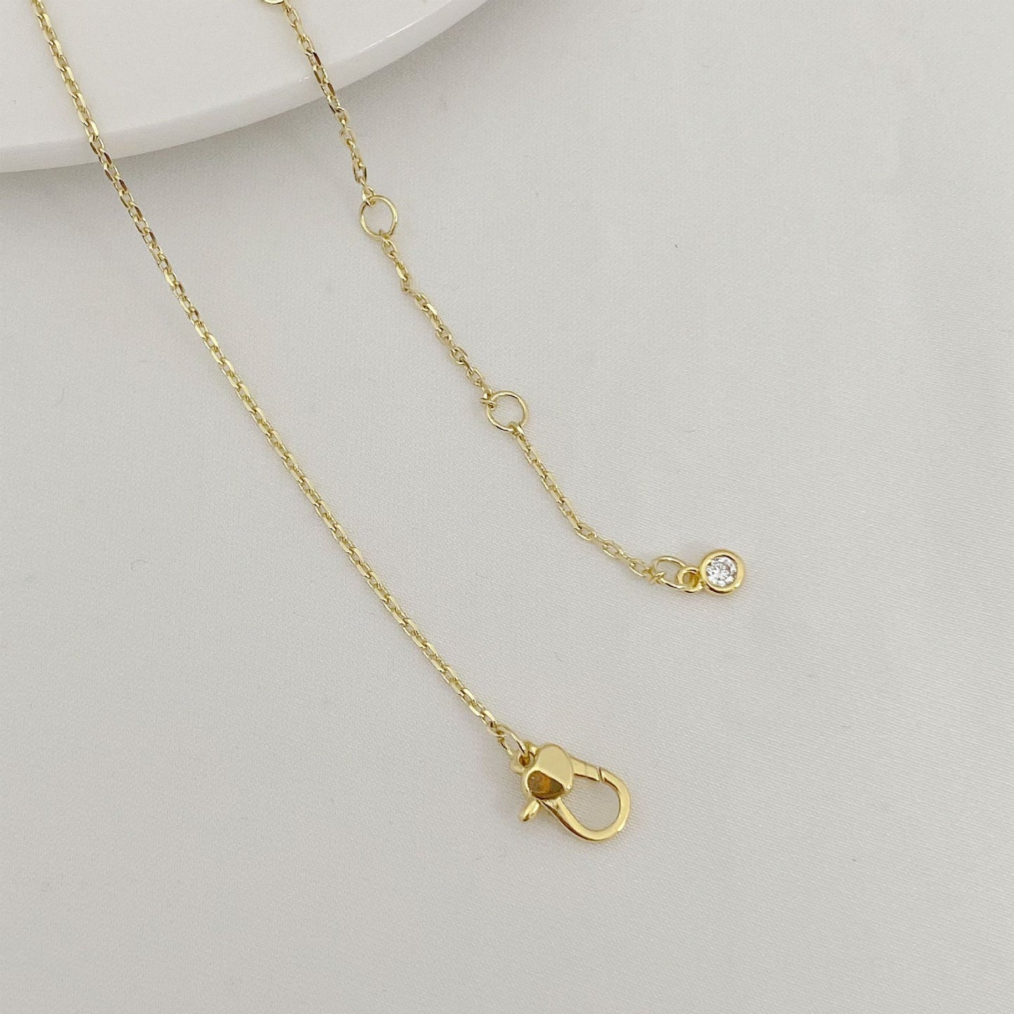 Gold necklace with a clasp on a light gray background