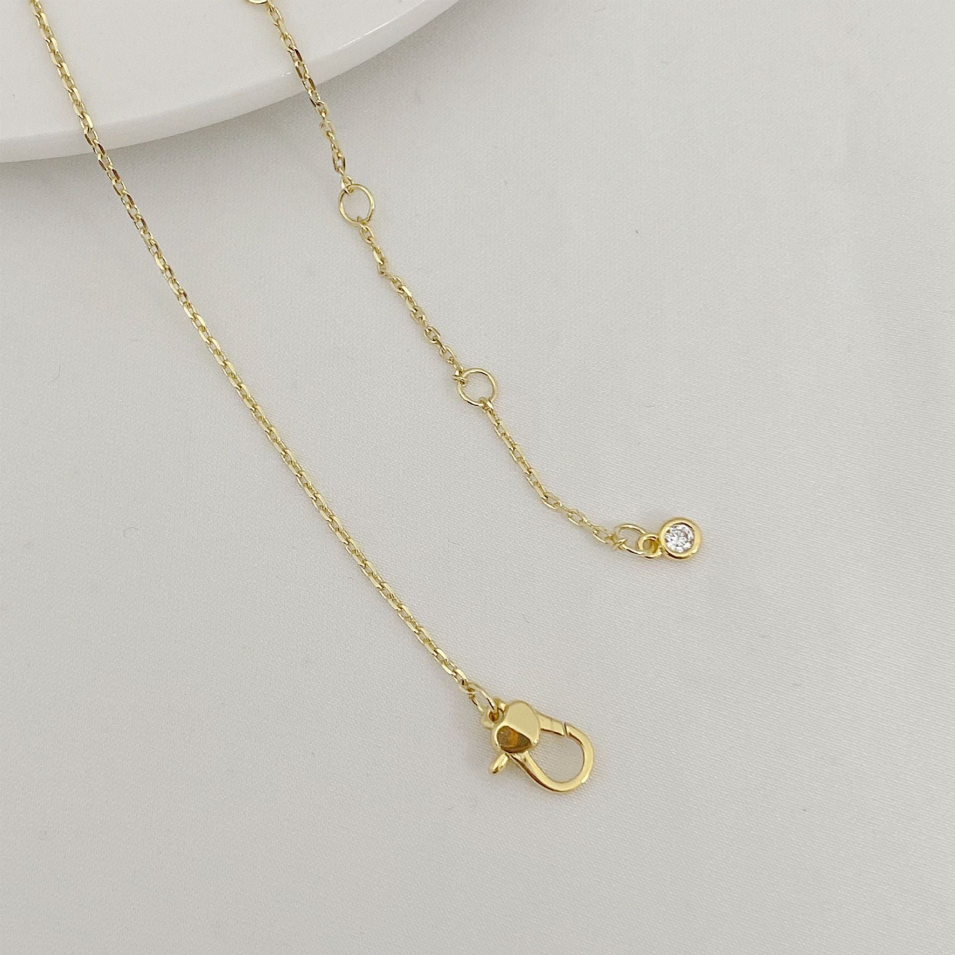 Gold necklace with a clasp on a light gray background