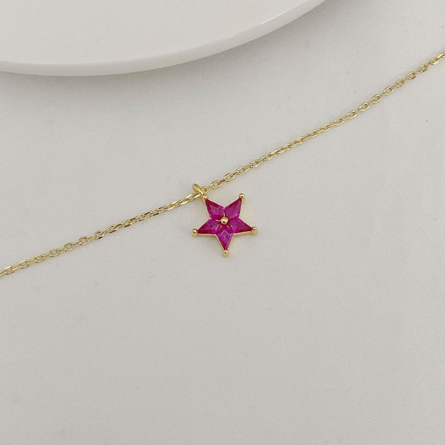 Gold necklace with a star-shaped pendant on a light gray background