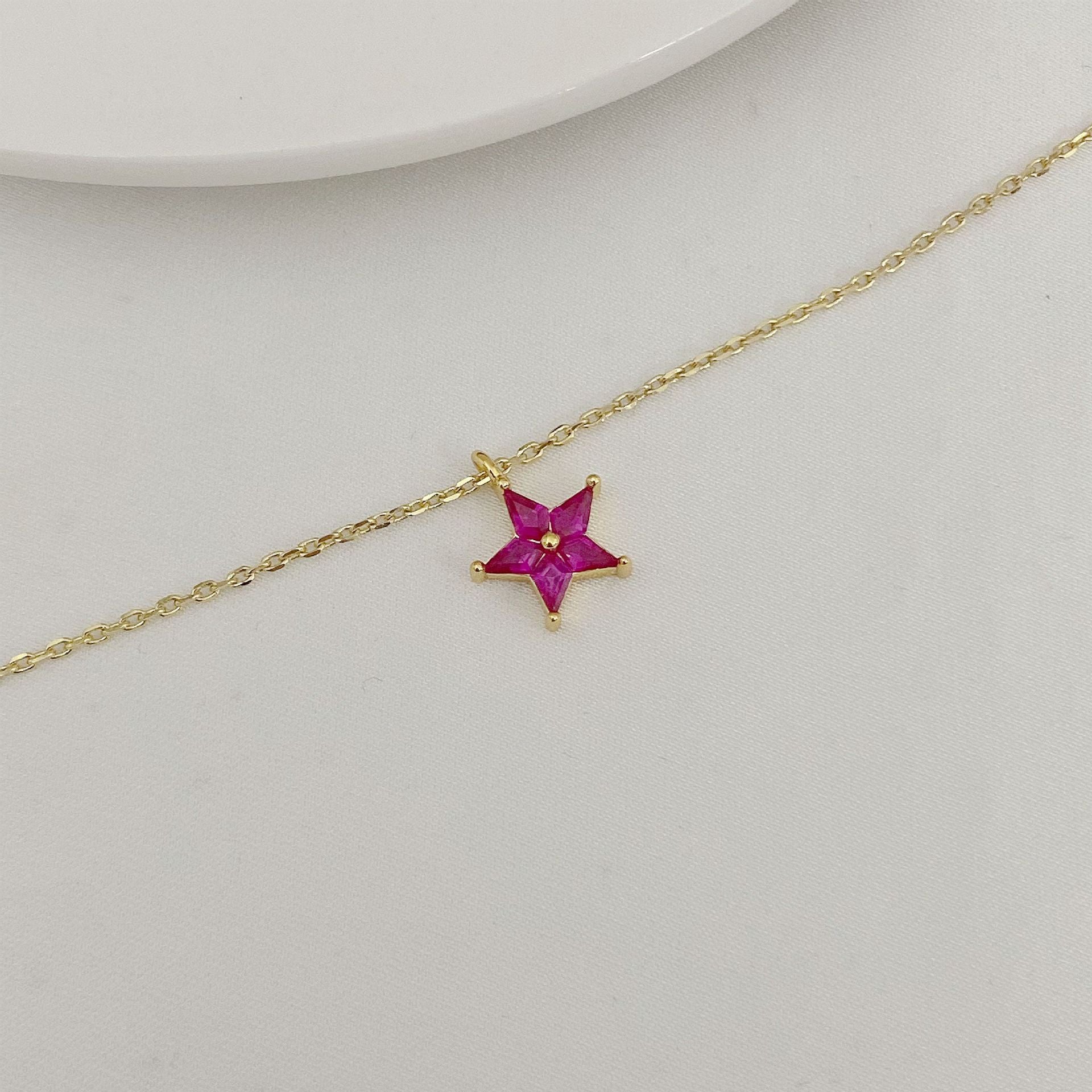 Gold necklace with a star-shaped pendant on a light gray background
