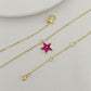 Gold necklace with a star-shaped pink gemstone pendant on a light gray background