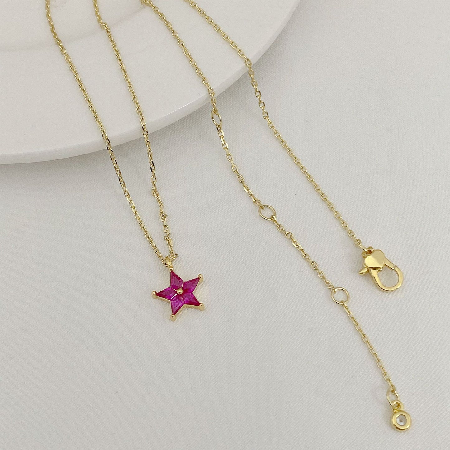 Gold necklace with a star-shaped pendant on a light gray background