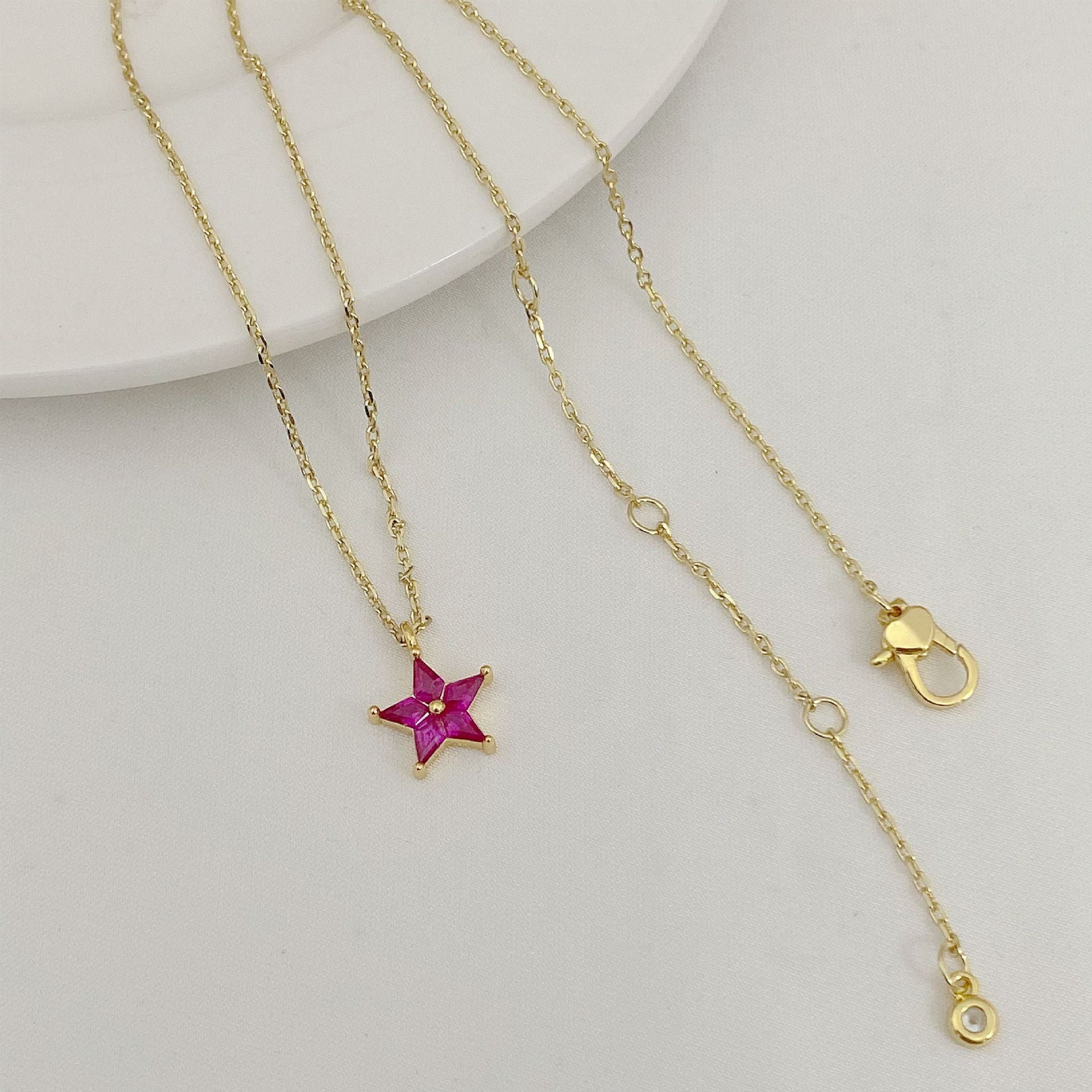 Gold necklace with a star-shaped pendant on a light gray background