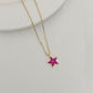 Gold necklace with a star-shaped pendant featuring a red gemstone on a light gray background