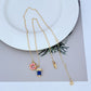 Necklace displayed against a soft pastel or marble background, highlighting the colorful charms. Alt: “Kate Spade Drink & Donut Necklace – Whimsical Food Charm Jewelry.”