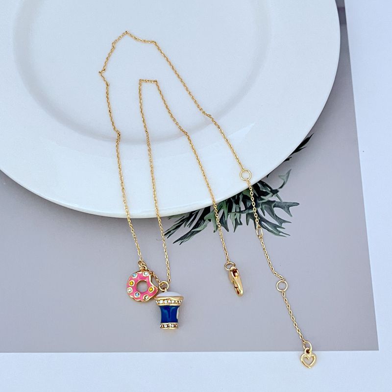 Necklace displayed against a soft pastel or marble background, highlighting the colorful charms. Alt: “Kate Spade Drink & Donut Necklace – Whimsical Food Charm Jewelry.”
