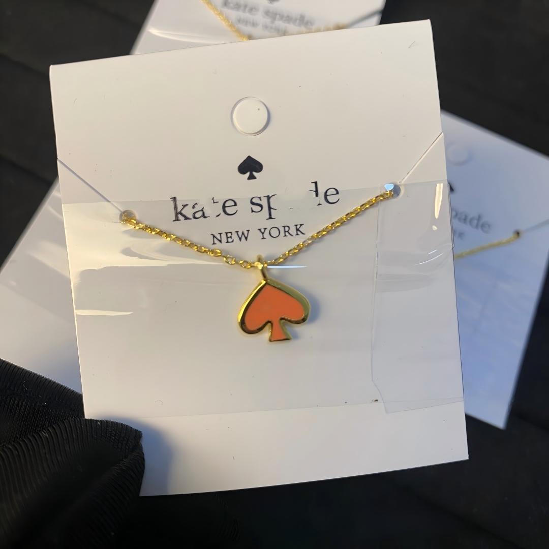 Gold necklace with orange pendant on a Kate Spade card