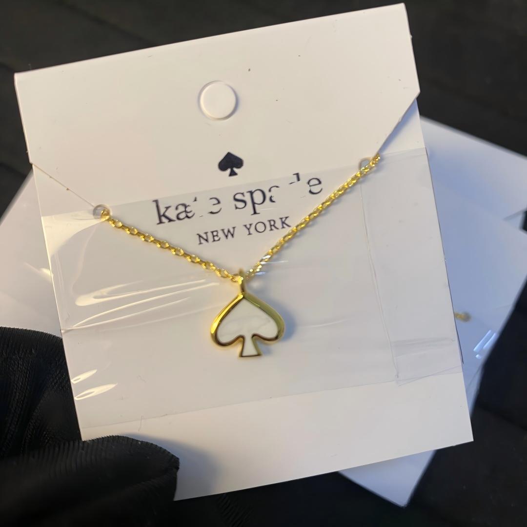 Gold necklace with a heart-shaped pendant on a Kate Spade card.
