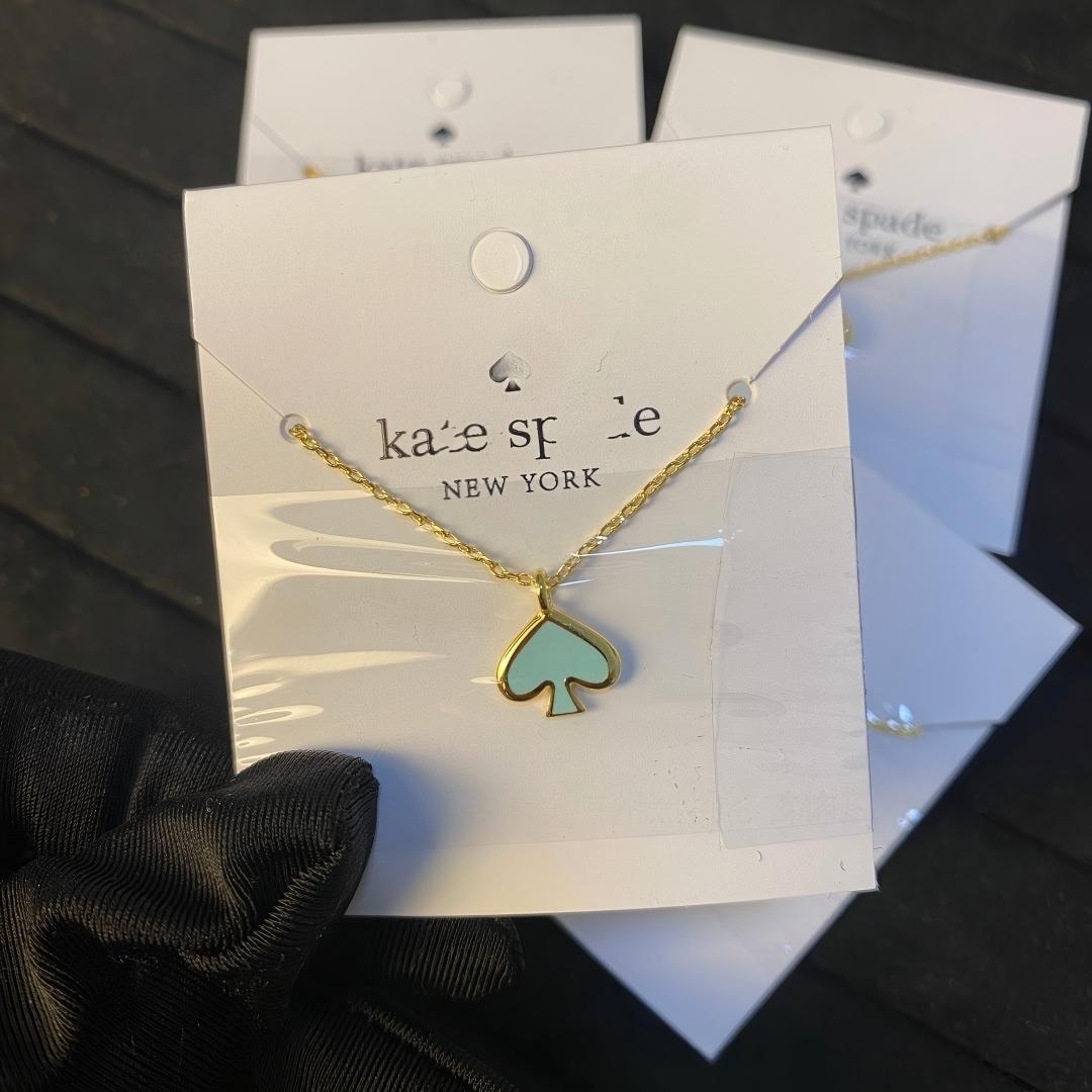 Gold necklace with a green pendant on a Kate Spade card.