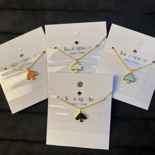 Three gold necklaces with spade-shaped pendants on display cards with 'kate spade New York' branding.
