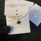 Gold necklace with a heart and spade pendant on a Kate Spade card.