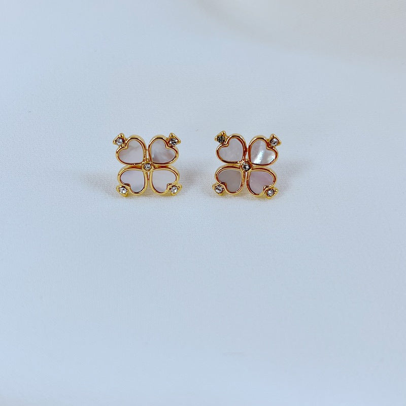 Gold-tone clover studs on a soft white background, showcasing green enamel or crystal detailing. Alt: “Kate Spade Gold Four Leaf Clover Earrings – Lucky Enamel Studs.”