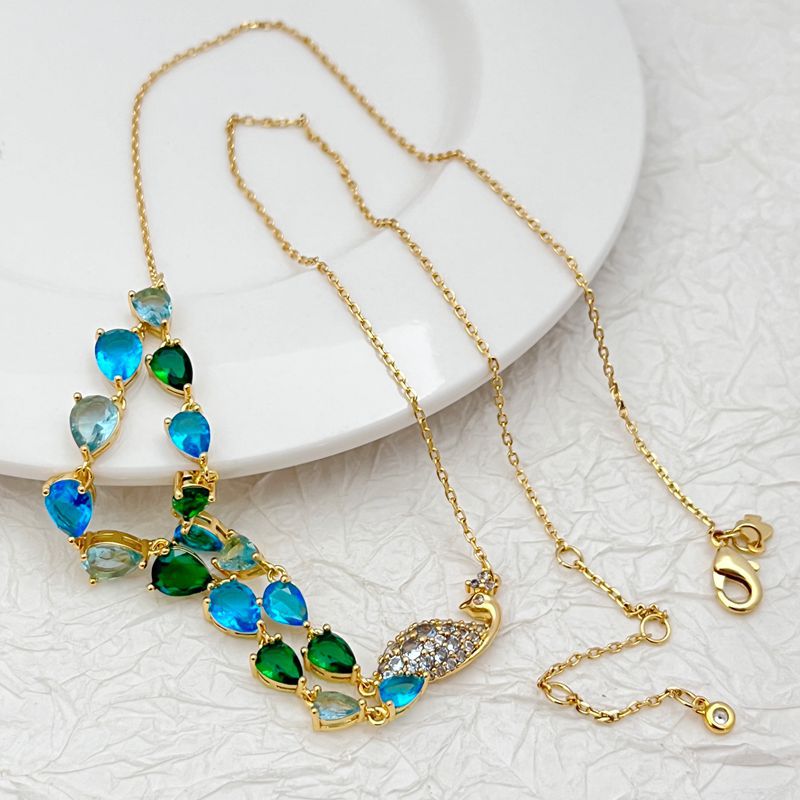 Necklace laid flat on a light neutral background, highlighting the gold setting and vibrant blue/green gemstones. Alt: “Kate Spade Gold Necklace with Blue and Green Gemstones – Colorful Pendant Jewelry.