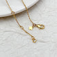 Necklace laid flat on a light neutral background, highlighting the gold setting and vibrant blue/green gemstones. Alt: “Kate Spade Gold Necklace with Blue and Green Gemstones – Colorful Pendant Jewelry.