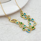 Necklace laid flat on a light neutral background, highlighting the gold setting and vibrant blue/green gemstones. Alt: “Kate Spade Gold Necklace with Blue and Green Gemstones – Colorful Pendant Jewelry.