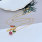 Necklace on a rustic wood or green linen background, highlighting the colorful veggie charm. Alt: “Kate Spade Harvest Time Veggie Charm Pendant Necklace – Playful Garden Jewelry.”