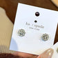 Silver floral earrings on a Kors & Spade card with a blurred background