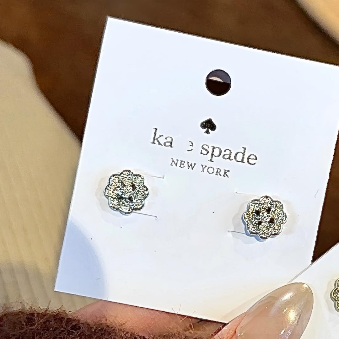 Silver floral earrings on a Kors & Spade card with a blurred background