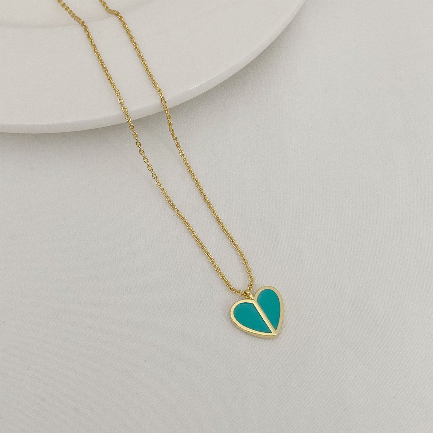 Straight-on to clearly showcase the mini heart pendant with vibrant red enamel and the signature spade detail.
