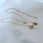 Clean, macro shot of the necklace on a plain background, emphasizing the petite charm and fine chain.