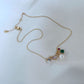 Clean, macro shot of the necklace on a plain background, emphasizing the petite charm and fine chain.