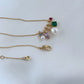 Clean, macro shot of the necklace on a plain background, emphasizing the petite charm and fine chain.