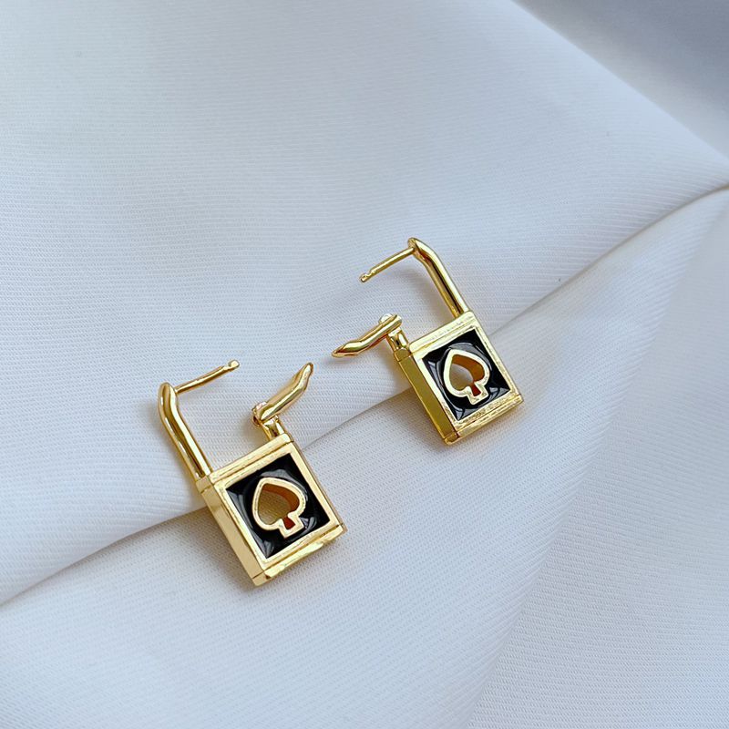 Earrings on a soft black or charcoal background, showcasing the gold spade and padlock charms with black enamel details. Alt: “Kate Spade Lock & Spade Earrings Black & Gold – Signature Enamel Drop Jewelry.”